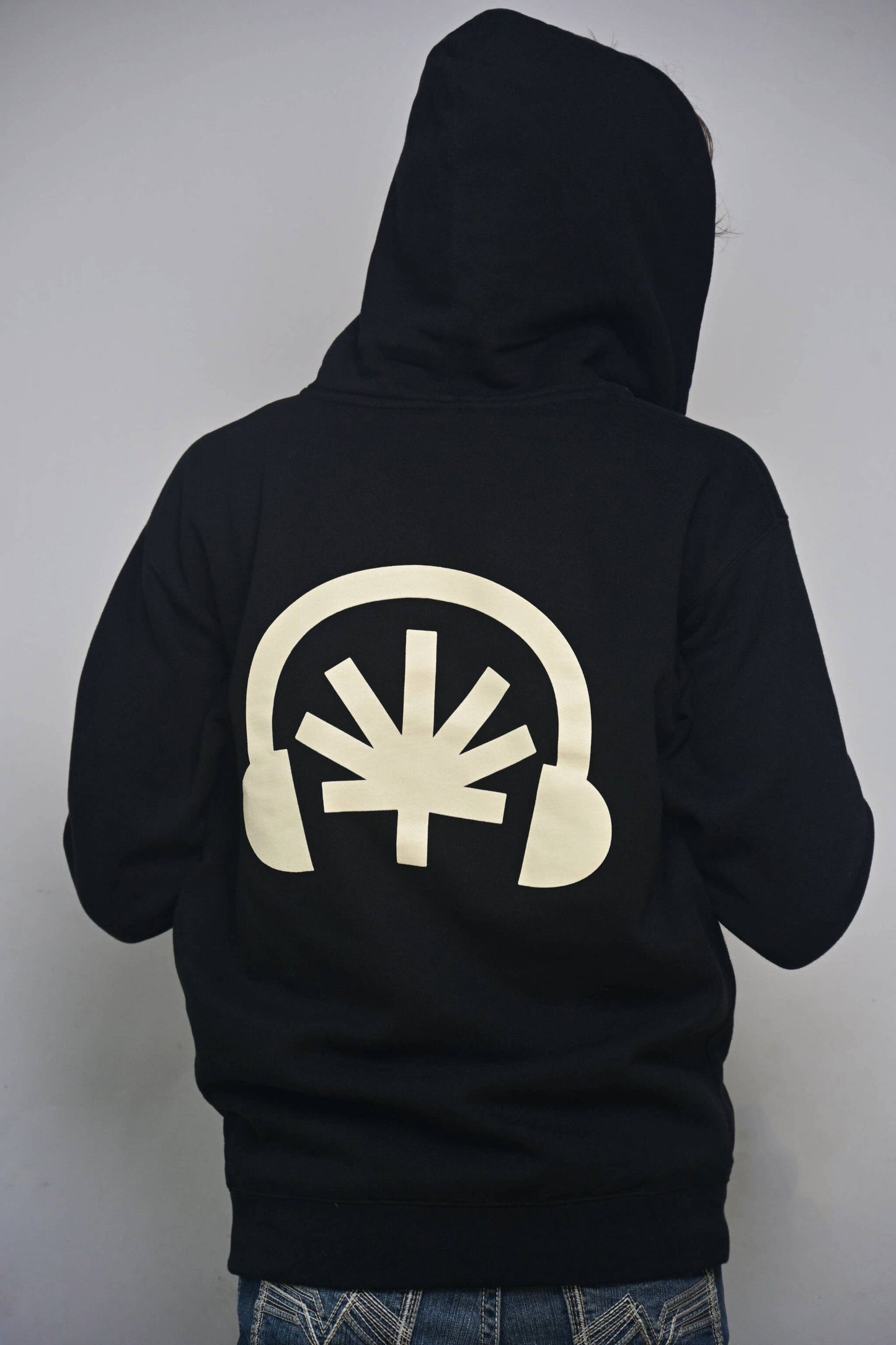 Black zip hoodie with oversized cream Headphones back graphic with stylized cannabis leaf (back, on-model)