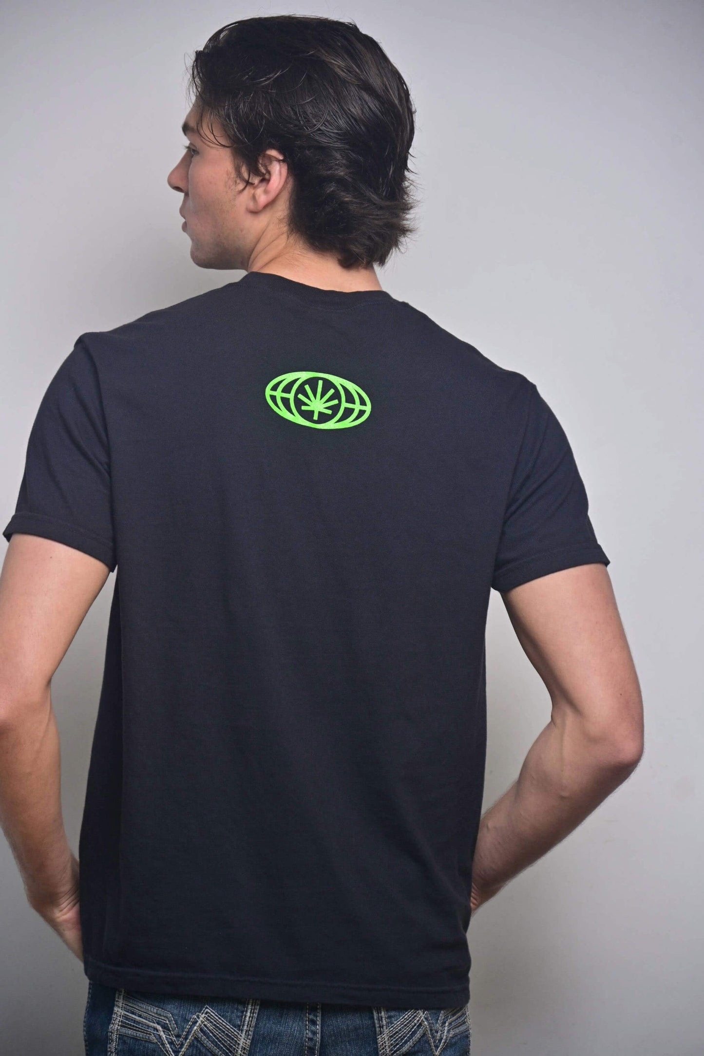 Black tee with small VYLIN globe icon centered ~3 in below back neckline (back, on-model)
